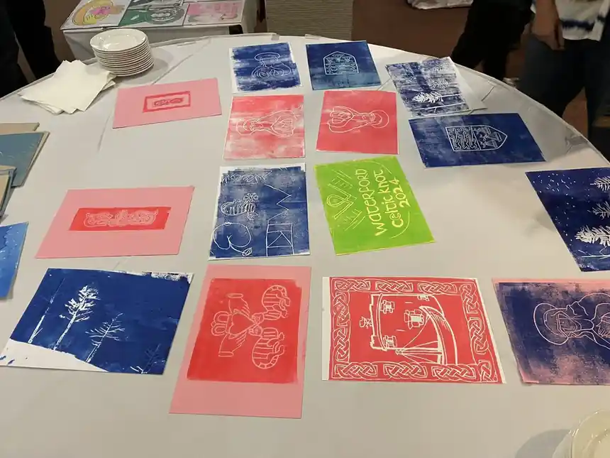 Linogravures fraîchement tirées en rose, bleu et vert, posées à sécher sur une table
